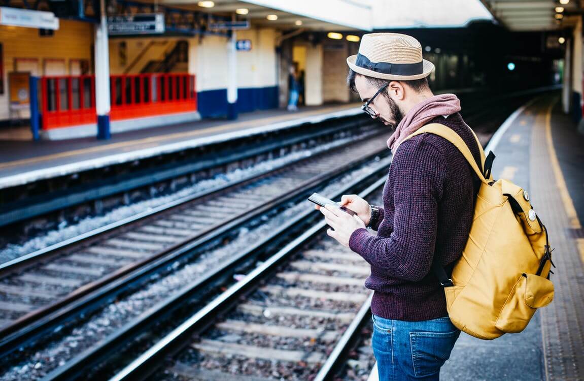 Homem usando o celular em estação de trem